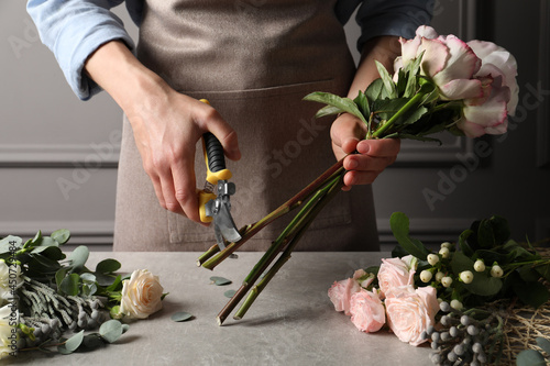 фотографія Florist cutting flower stems with pruner at workplace, closeup