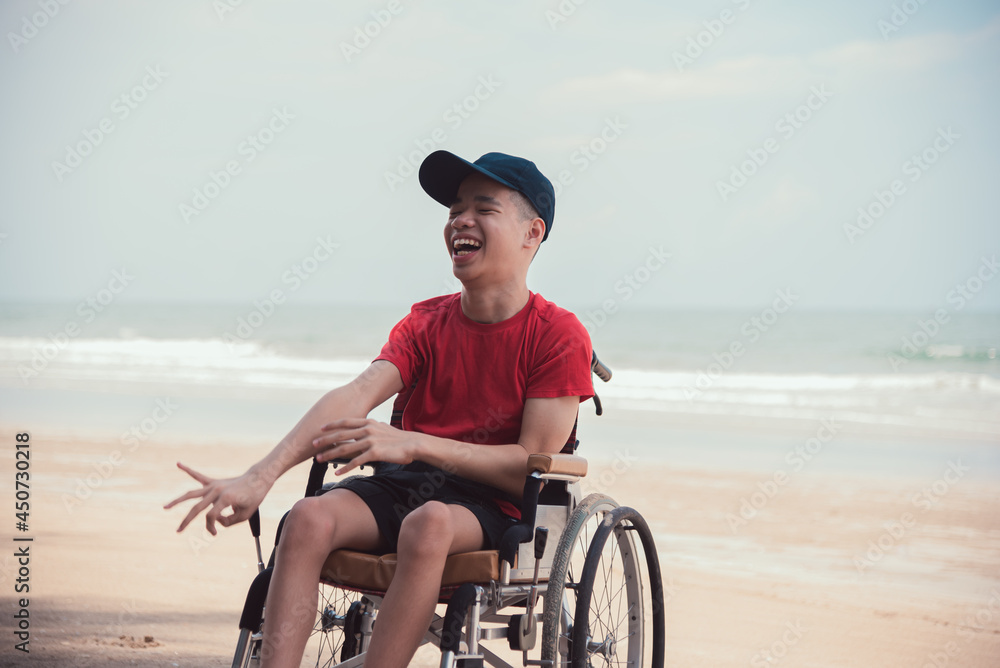 Asian happy disabled teenage boy, Activity outdoors with family on the beach background, People having fun and diverse people concept.