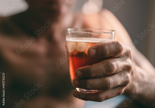 Liquor glass in the hands of a middle-aged man, concept of poor man alcohol addiction and depression because of life problems, Strain during the economy has stalled due to covid pandemic, Cinema tone.