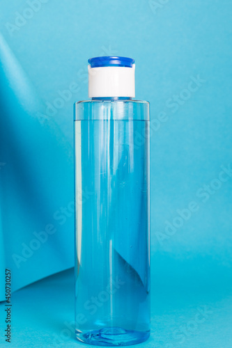 Art colourful geometry blue style and skin care cosmetics. Origami in a blue colour and cosmetics in white and blue colours: serum, face cream, face tonic. Paper mock up and luxury cosmetic. 