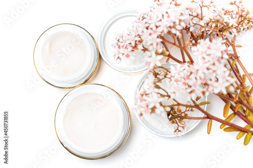 cosmetics for the face. eye cream and a bunch of pink flowers on a white background