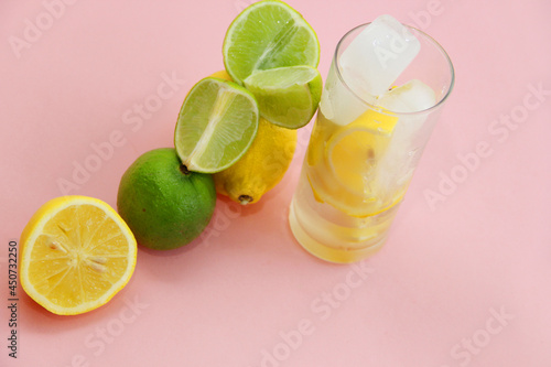 cocktail with lemon, lime and min. lime and lemon on a pink background.lime slices and lemon in the cut