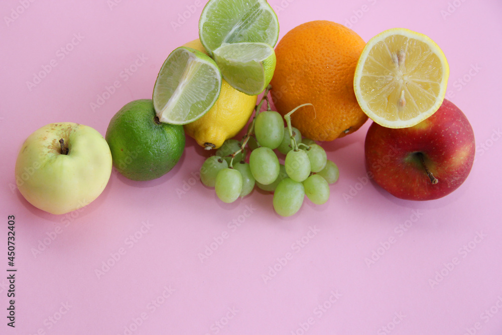 fresh fruit apple, lime, avocado, lemon, orange, grapes on a light pink background fresh fruit apple, lime, avocado, lemon, orange, grapes on a light pink background