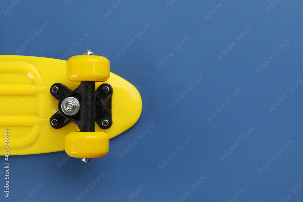 Yellow skateboard on blue background, top view. Space for text Yellow skateboard on blue background, top view. Space for text