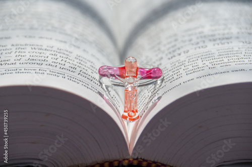 Close up glass crucifix on open bible page on blue background. Concept of hope, faith, love, symbol christianity, religion, church online, Easter time, Christmas, Jesus loves you, with Copy Space