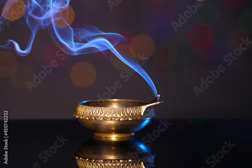 Blown out diya on dark background with blurred lights. Diwali lamp photo