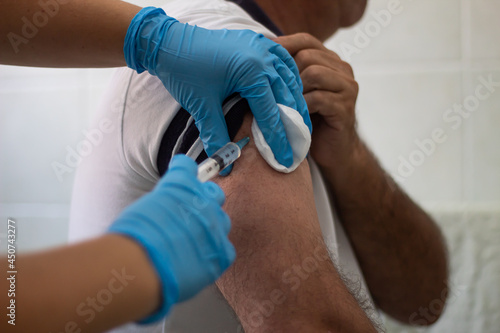 nurse is injecting the vaccine to a man