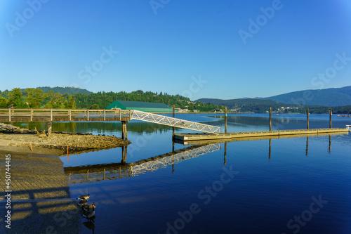 Access ramp to floating dock on Burrard Inlet at Rocky Point Park, Port Moody, BC with Canada geese in foreground and residences of UniverCity Highlands just visible atop Burnaby Mountain