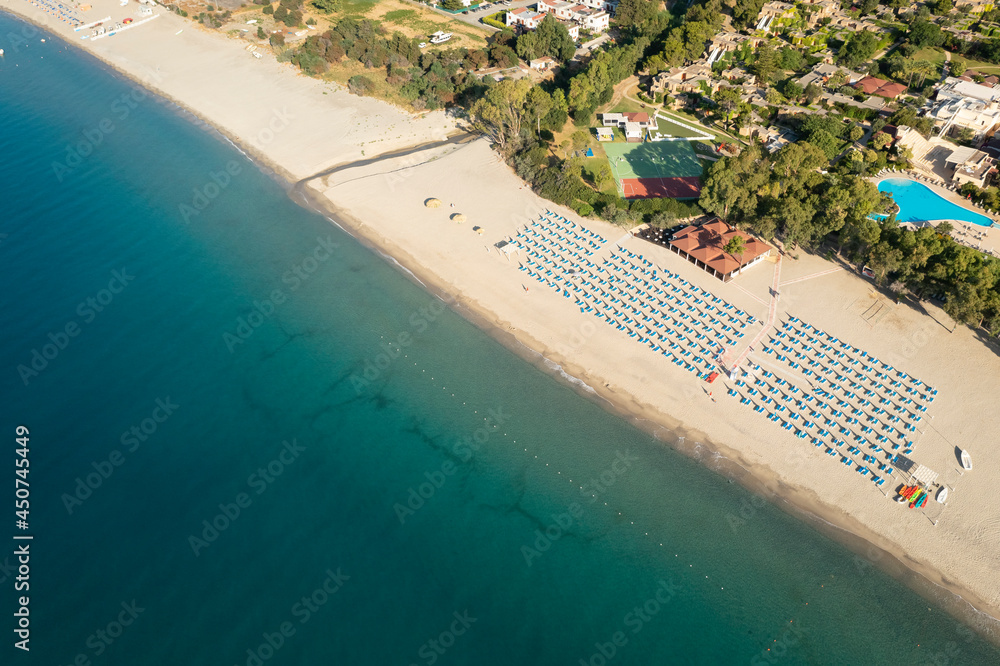 Drone shot of beautiful sea and beach with parasol at sunny day, Simeri Mare, Calabria, Southern Italy