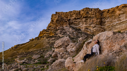 Italian young girl admires the view from cliff in Malta