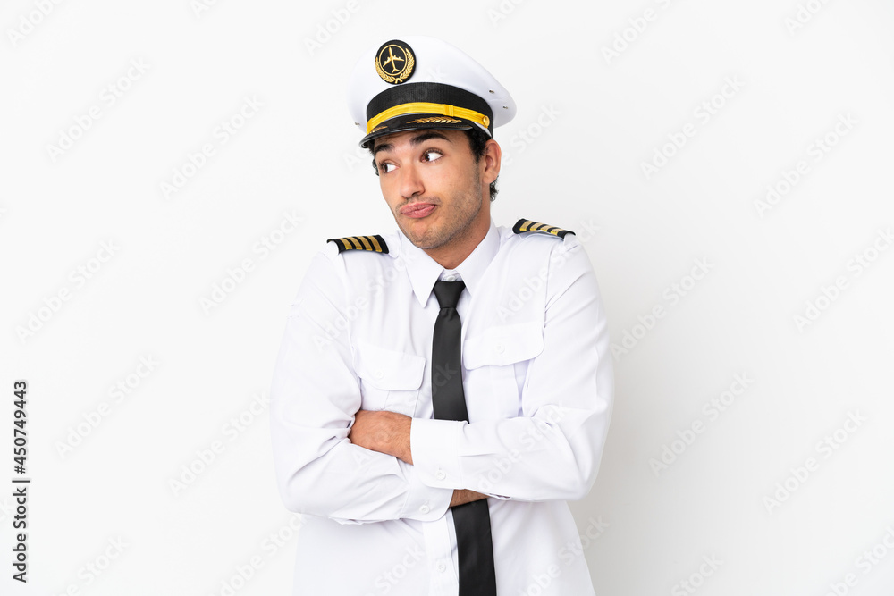 Airplane pilot over isolated white background making doubts gesture while lifting the shoulders Airplane pilot over isolated white background making doubts gesture while lifting the shoulders