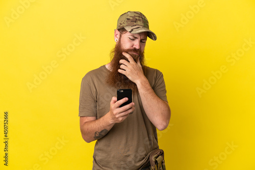 Redhead Military man with dog tag isolated on yellow background thinking and sending a message © luismolinero