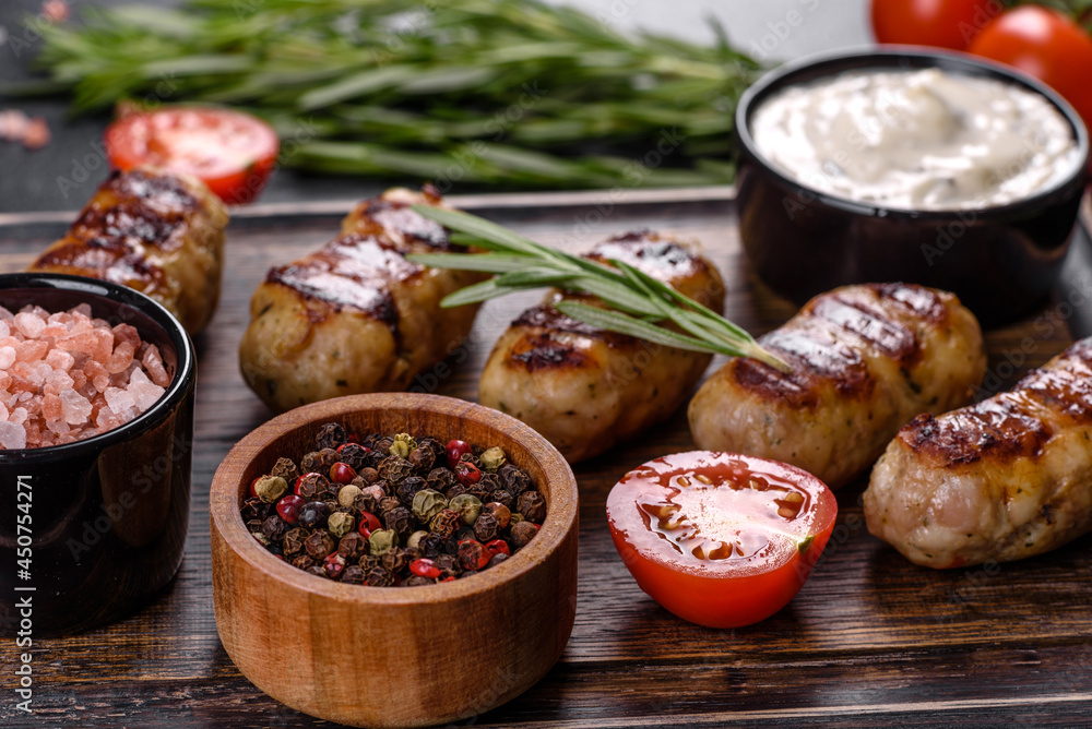 Grilled sausage with the addition of herbs and vegetables on the dark background Grilled sausage with the addition of herbs and vegetables on the dark background