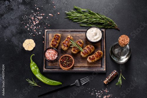 Grilled sausage with the addition of herbs and vegetables on the dark background
