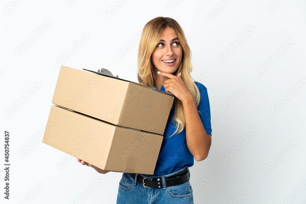 Young blonde Uruguayan delivery woman isolated on white background looking up while smiling Young blonde Uruguayan delivery woman isolated on white background looking up while smiling