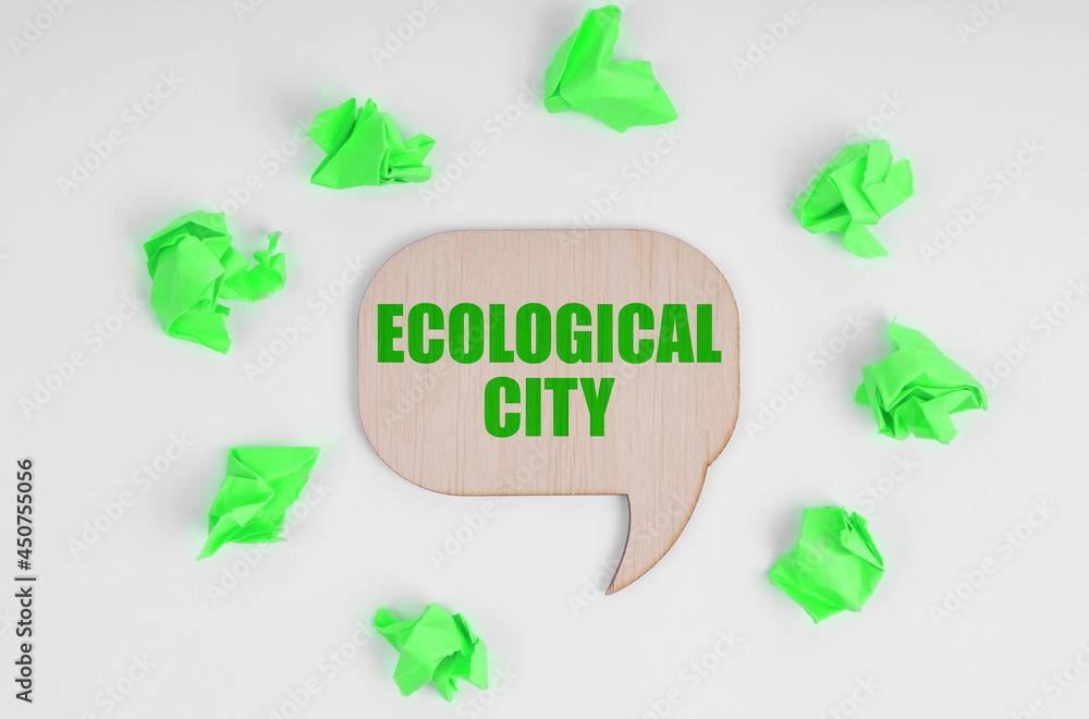 On a white background, there are crumpled green pieces of paper and a wooden sign with the inscription - Ecological City On a white background, there are crumpled green pieces of paper and a wooden sign with the inscription - Ecological City