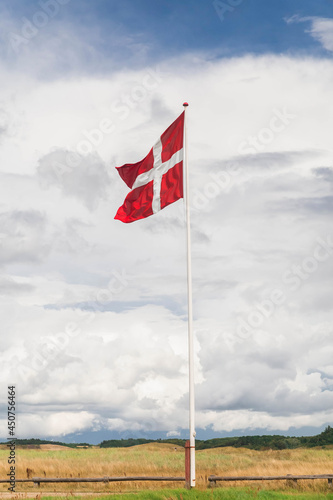 Danish flag on a flagpole against a beautiful cloudy sky