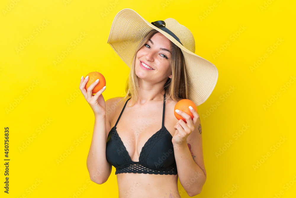 Young Romanian woman isolated on yellow background in swimsuit and holding a cocktail Young Romanian woman isolated on yellow background in swimsuit and holding a cocktail