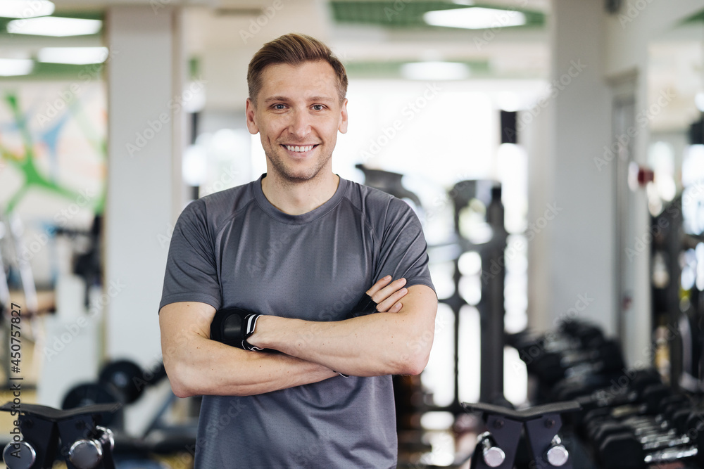 Young muscular man resting in gym while looking at camera. Portrait of competitive sportsman at wellness center. Determined guy taking a break after working out session. Young muscular man resting in gym while looking at camera. Portrait of competitive sportsman at wellness center. Determined guy taking a break after working out session.