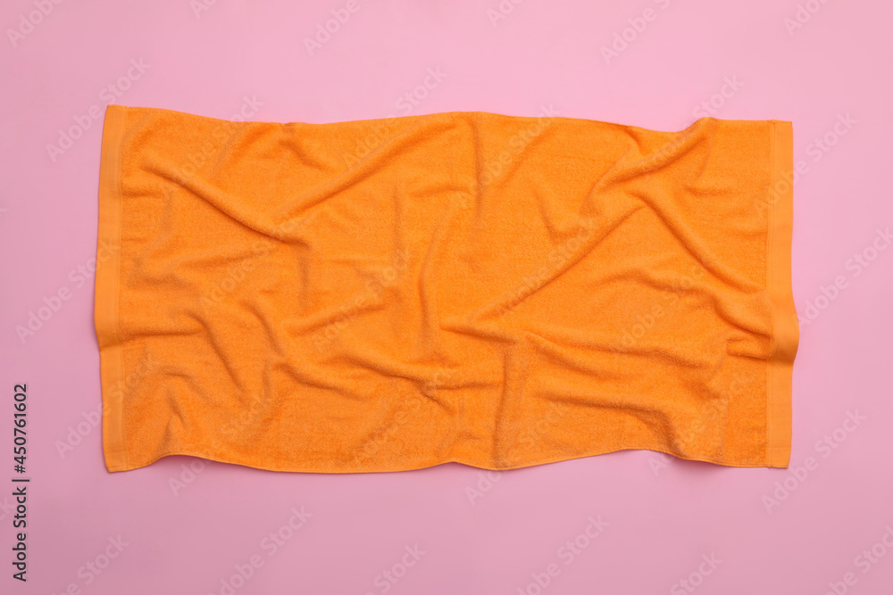 Crumpled orange beach towel on pink background, top view Crumpled orange beach towel on pink background, top view
