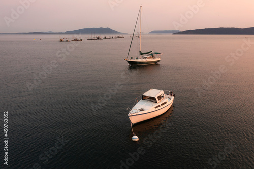 Boats Anchored in the San Juan Islands During a Beautiful Sunset. With reefnet salmon fishing boats in the background two pleasure boats anchor in Legoe Bay just off the Lummi Island coastline. photo