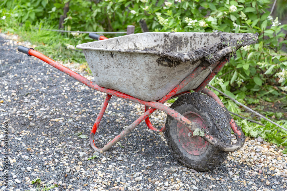 Iron wheel barrow for moving of building materials in the garden and in the backyard Iron wheel barrow for moving of building materials in the garden and in the backyard