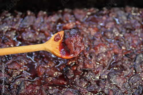 Boiled plums in a wooden spoon at home in the kitchen. The process of making plum jam