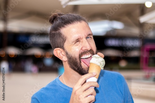 Young man with a cornet ice cream tasting it.