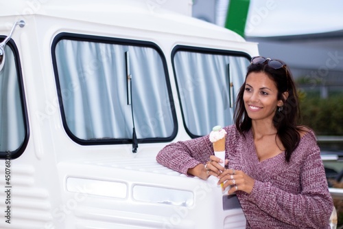 Young Woman having a ice cream in front of Ice Cream Van in Barcelona. Retro van.