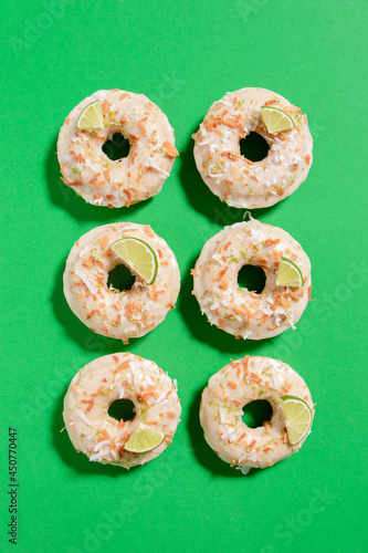Homemade key lime donuts with a toasted coconut topping on a bright green background