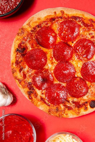 Close up of a homemade pepperoni pizza on a bright red background