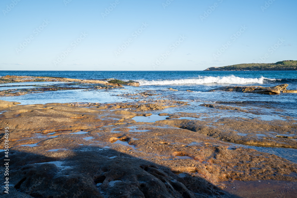 Fototapeta premium view of waves hitting rocks at the seaside