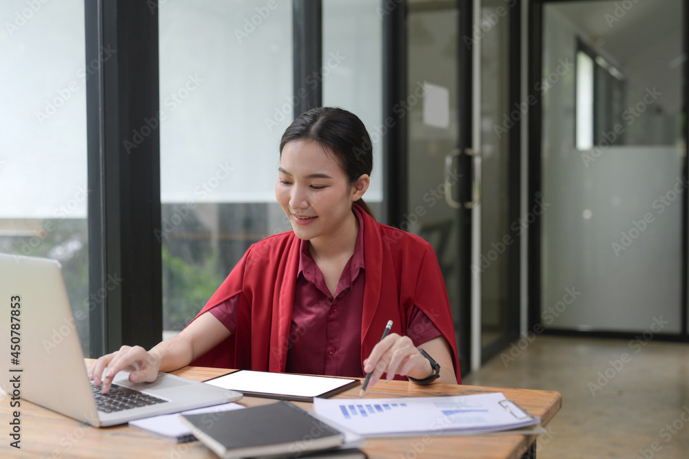 Smiling businesswoman sitting near window in office and working with laptop. Smiling businesswoman sitting near window in office and working with laptop.