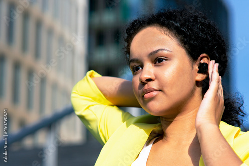 Black girl, African American listens to music in wireless headphones.Portrait of a beautiful young swarthy woman talking bluetooth earphone