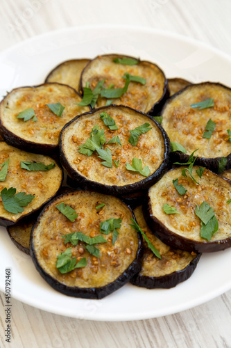 Homemade Organic Roasted Eggplant on a white plate on a white wooden background, side view. Close-up.