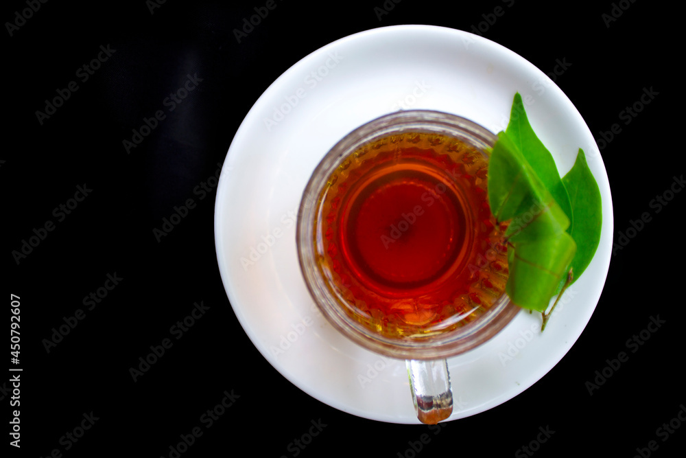 Black tea isolated on black background with tender tea leaves. Green tea in a glass cup. Black tea isolated on black background with tender tea leaves. Green tea in a glass cup.