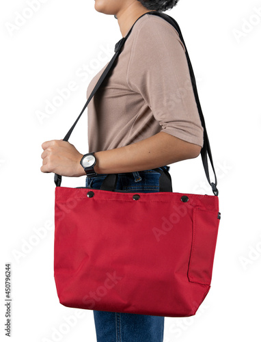 Isolated close up studio shot of female model in brown long sleeve shirt and jeans stand hanging big red multipurpose unisex traveling sport folding bicycle bag on shoulder on white background