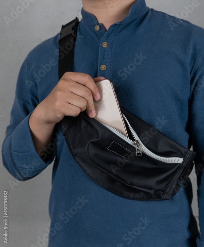Foto Closeup studio shot of male model in blue long sleeve shirt putting smartphone i