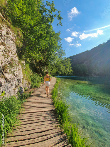 VERTICAL: Unrecognizable woman explores the Plitvice national park on sunny day