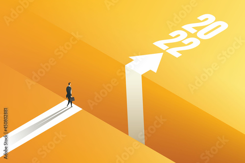 Businessman standing on the edge of the gap with arrows to reach goal 2022