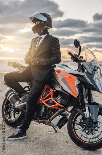 Cool businessman with motorcycle helmet posing against seascape