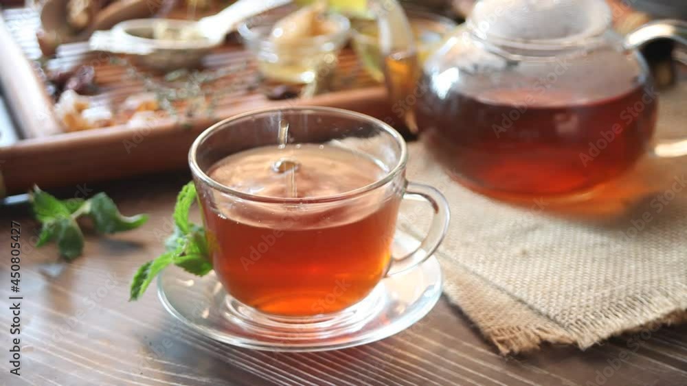 Cup of mint herbal tea with small bowl with honey on the tray. Cup of mint herbal tea with small bowl with honey on the tray.