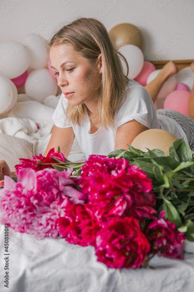 Image of a happy positive pretty young woman indoors at home in bedroom in bed holding flowers take a selfie by mobile phone. Image of a happy positive pretty young woman indoors at home in bedroom in bed holding flowers take a selfie by mobile phone.