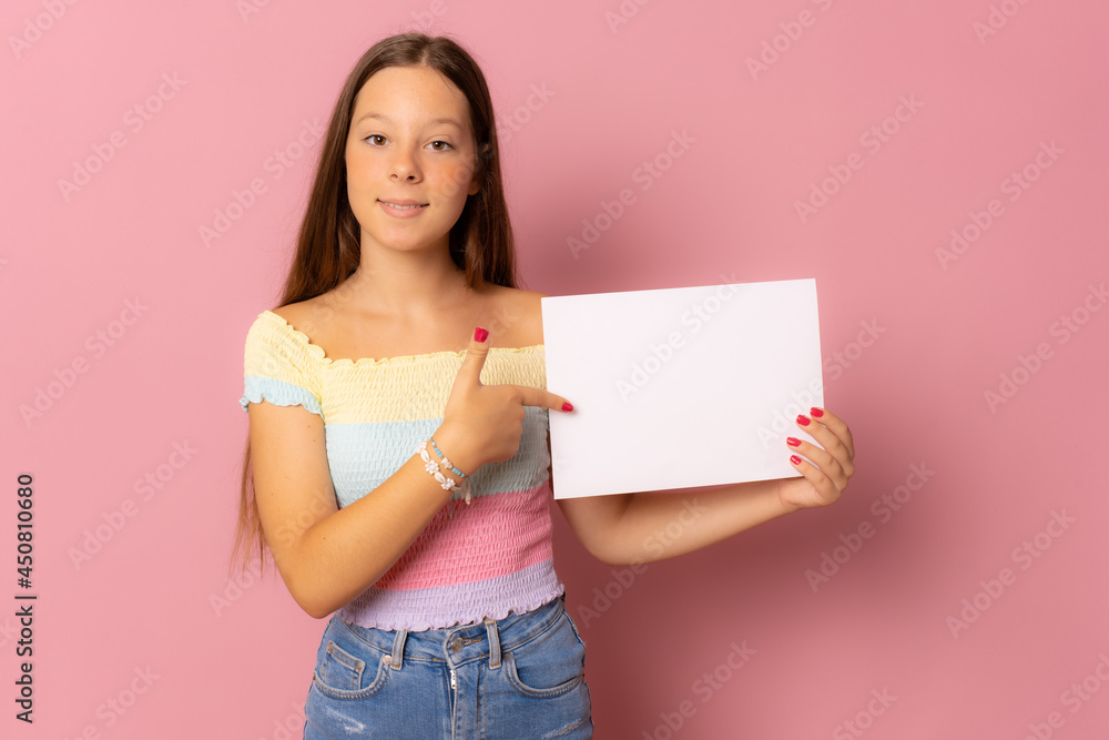 Young caucasian woman holding blank paper with smiling face and looking over pink background. Young caucasian woman holding blank paper with smiling face and looking over pink background.