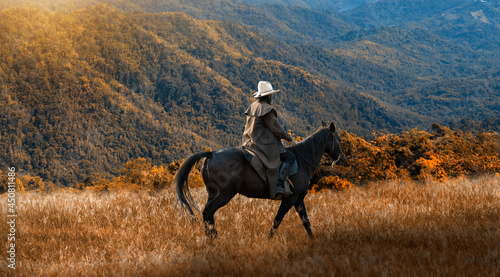 Cowboy horseback riding transportation at sunset time with green mountain and sunlight ray sky background. photo