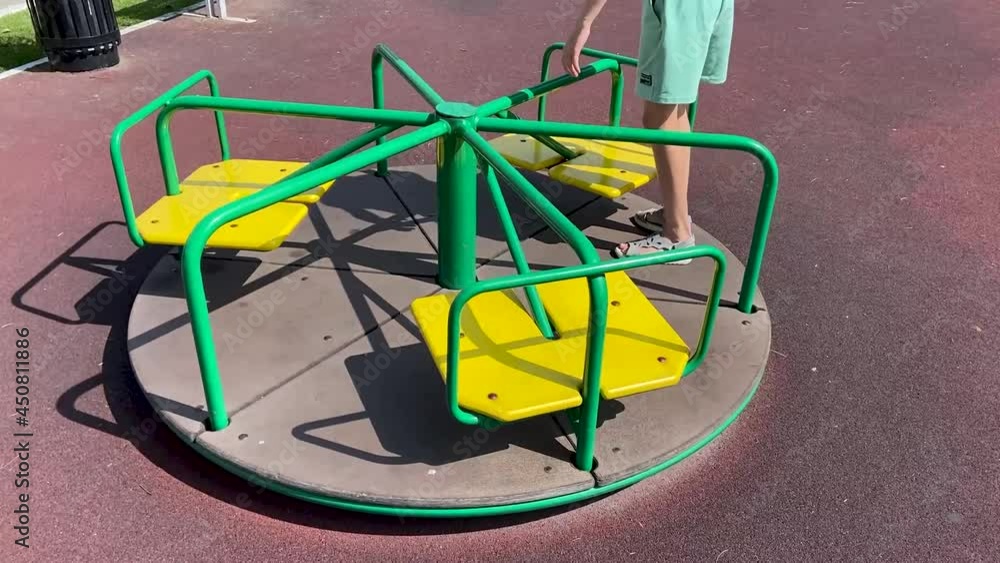 girl in shorts on a spinning carousel in the playground girl in shorts on a spinning carousel in the playground