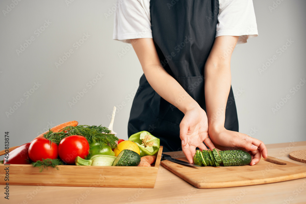 Woman in black apron cutting vegetables in the kitchen housewife preparing food Woman in black apron cutting vegetables in the kitchen housewife preparing food