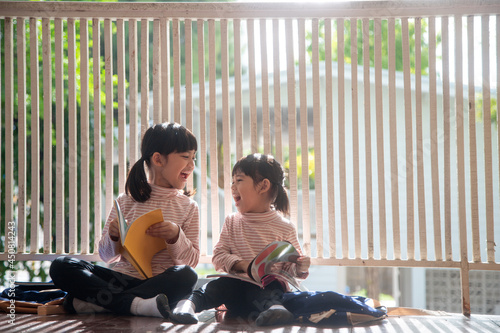 Photography Cute Asian siblings girl reading a book at home.