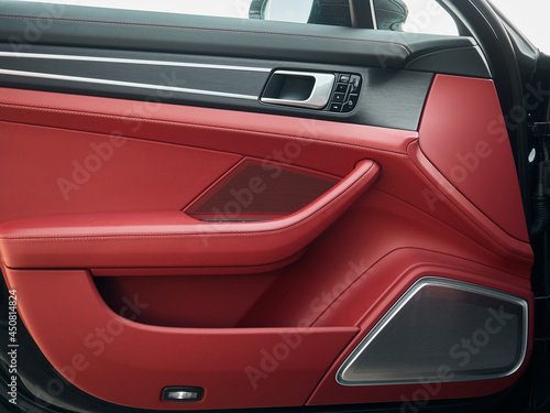 Control panel with chrome handle on the car door red genuine leather in a new car with arm rest with seat setting. © Владислав Винокуров