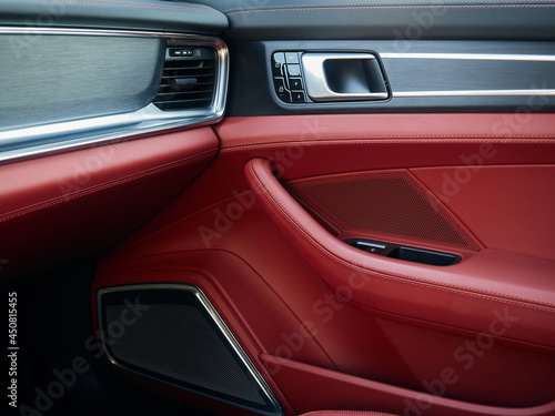 Control panel with chrome handle on the car door red genuine leather in a new car with arm rest with seat setting. © Владислав Винокуров